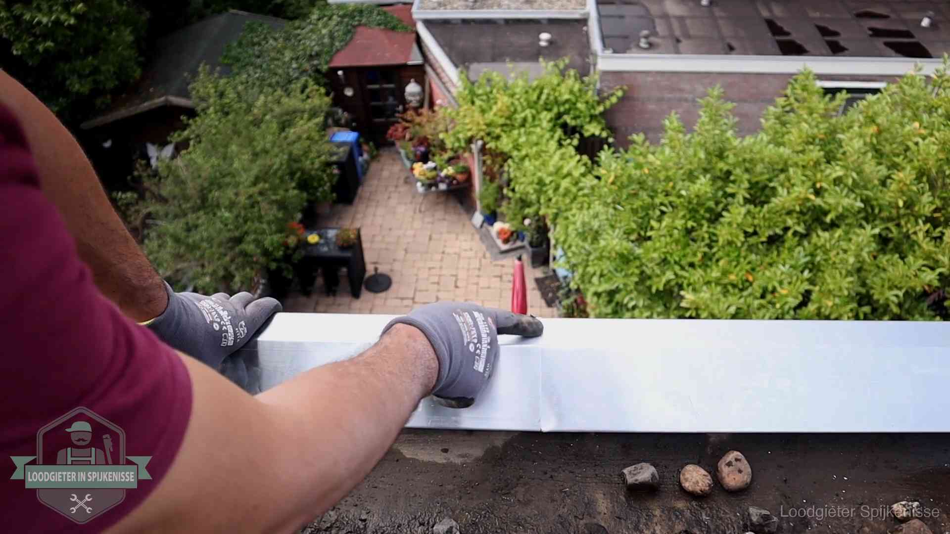 Daklekkage geregeld in Spijkenisse Vakman plaatst een daktrim op de dakrand van een woning in Spijkenisse