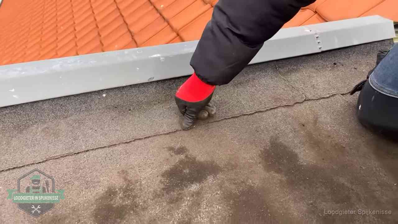 Lekkage bij de naad van een plat dak in Spijkenisse Vakman wijst een naad met vochtplekken aan op een bitumen plat dak in Spijkenisse