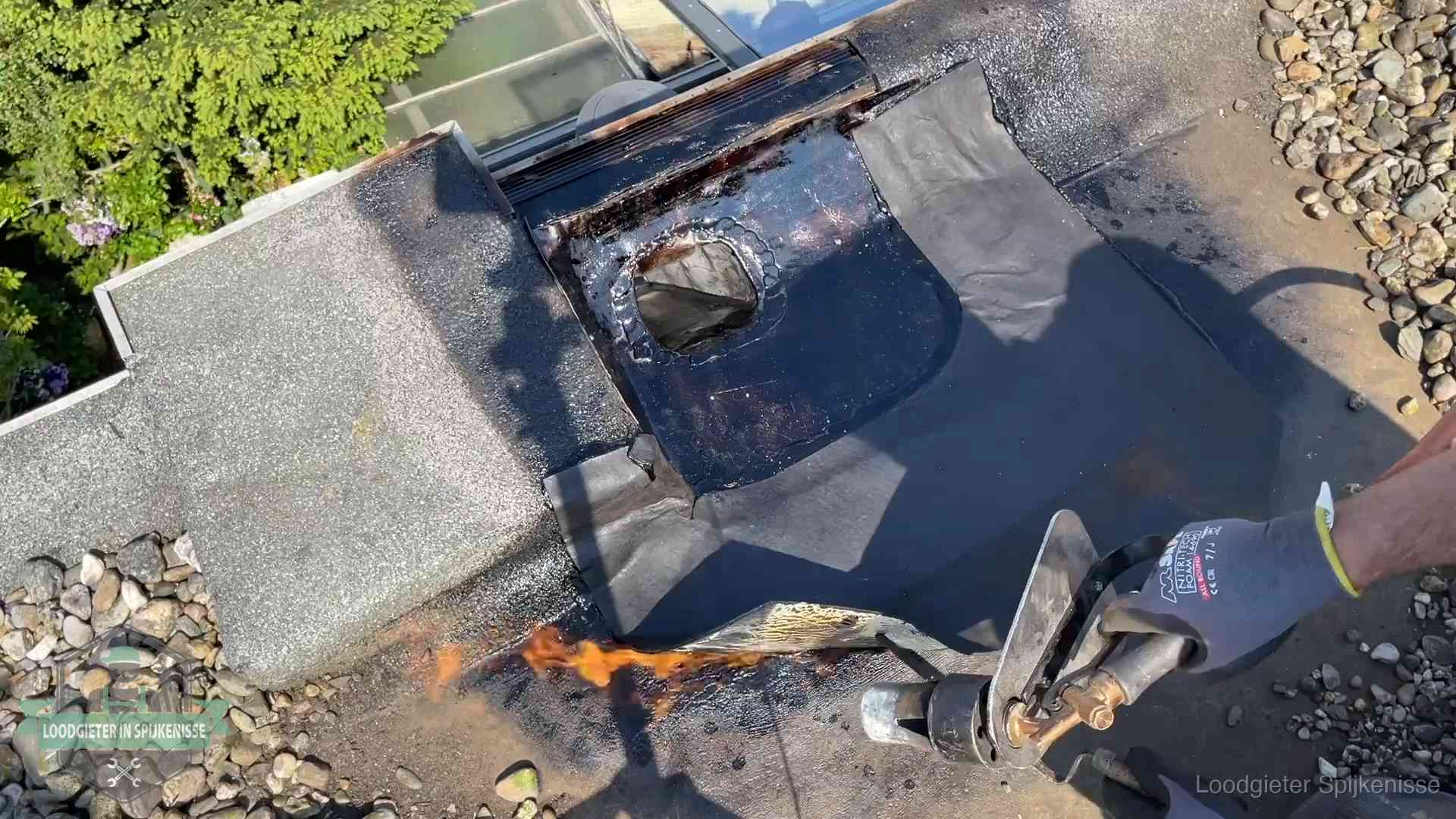 Daklekkage repareren in Spijkenisse Dakdekker brandt bitumen rond een doorvoer tijdens een daklekkage-reparatie in Spijkenisse