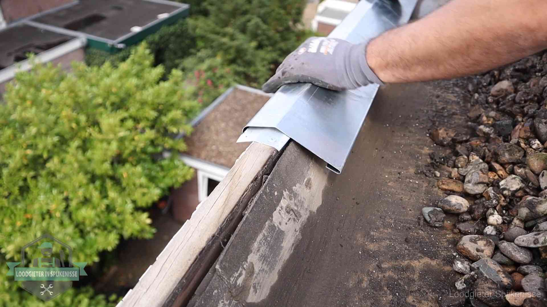 Daklekkage per wijk in Spijkenisse Dakdekker plaatst een zinken deklijst op een dakrand met uitzicht over een woonwijk in Spijkenisse