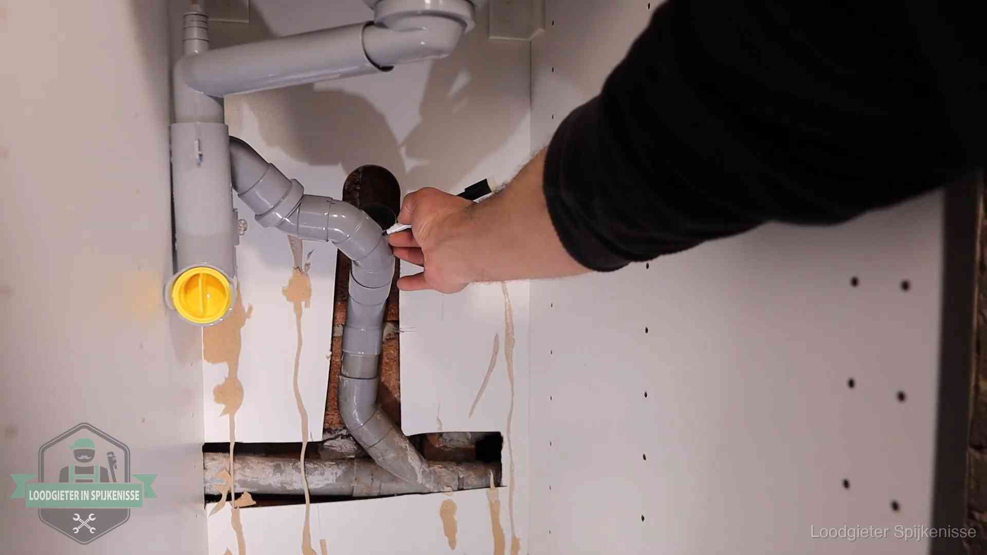 Loodgieter markeert een pvc-afvoerbuis onder een gootsteen in Spijkenisse