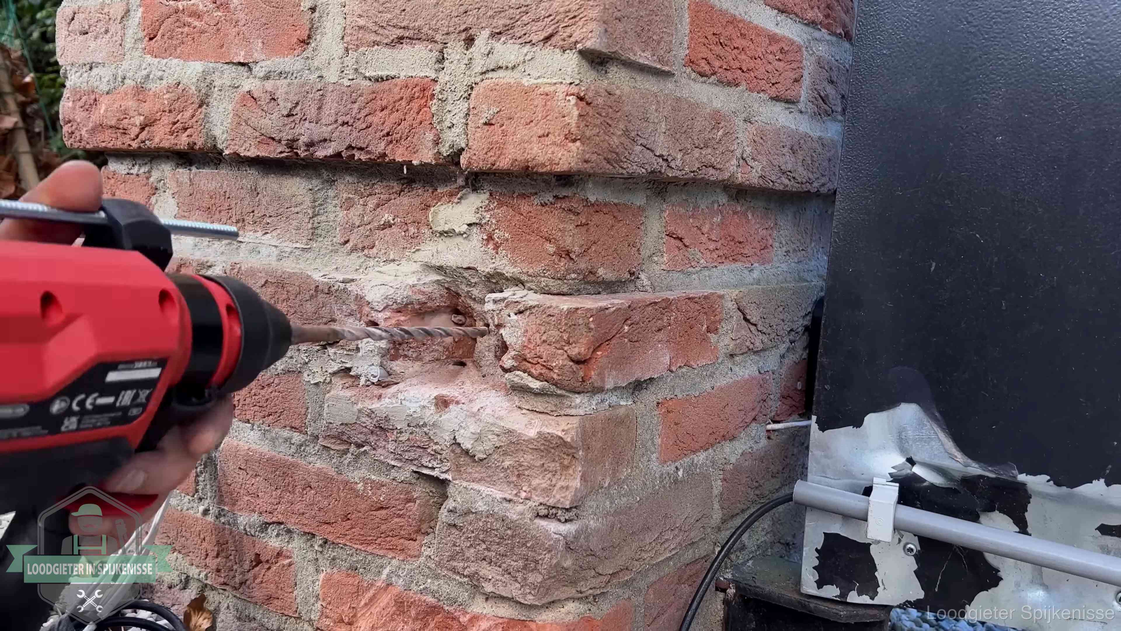 Vakman boort in de buitenmuur van een woning in de regio Spijkenisse