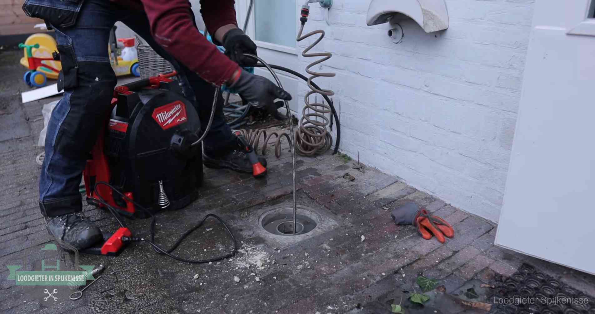 Ontstoppingsputje in de bestrating naast de gevel van een woning in Spijkenisse