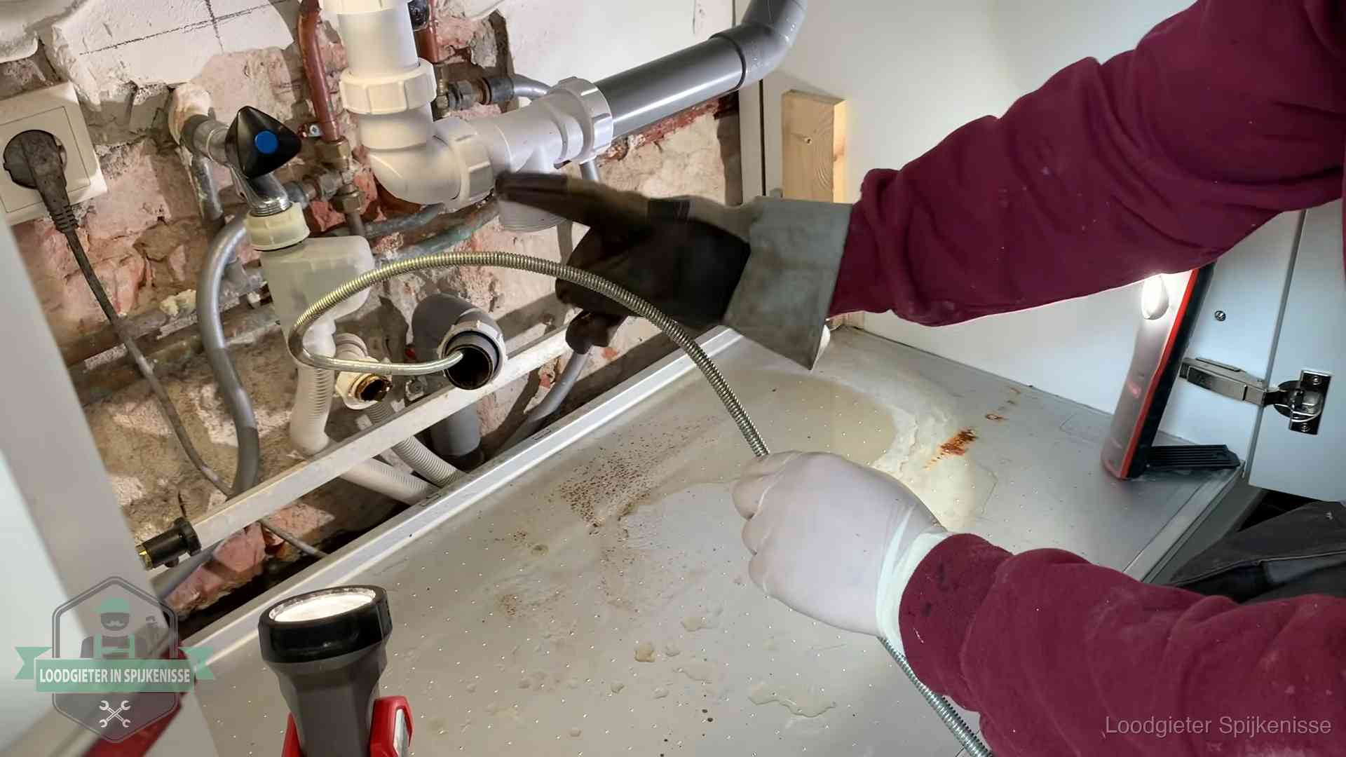 Ontstoppingsveer gaat in een geopende sifonaansluiting onder het aanrecht in Spijkenisse