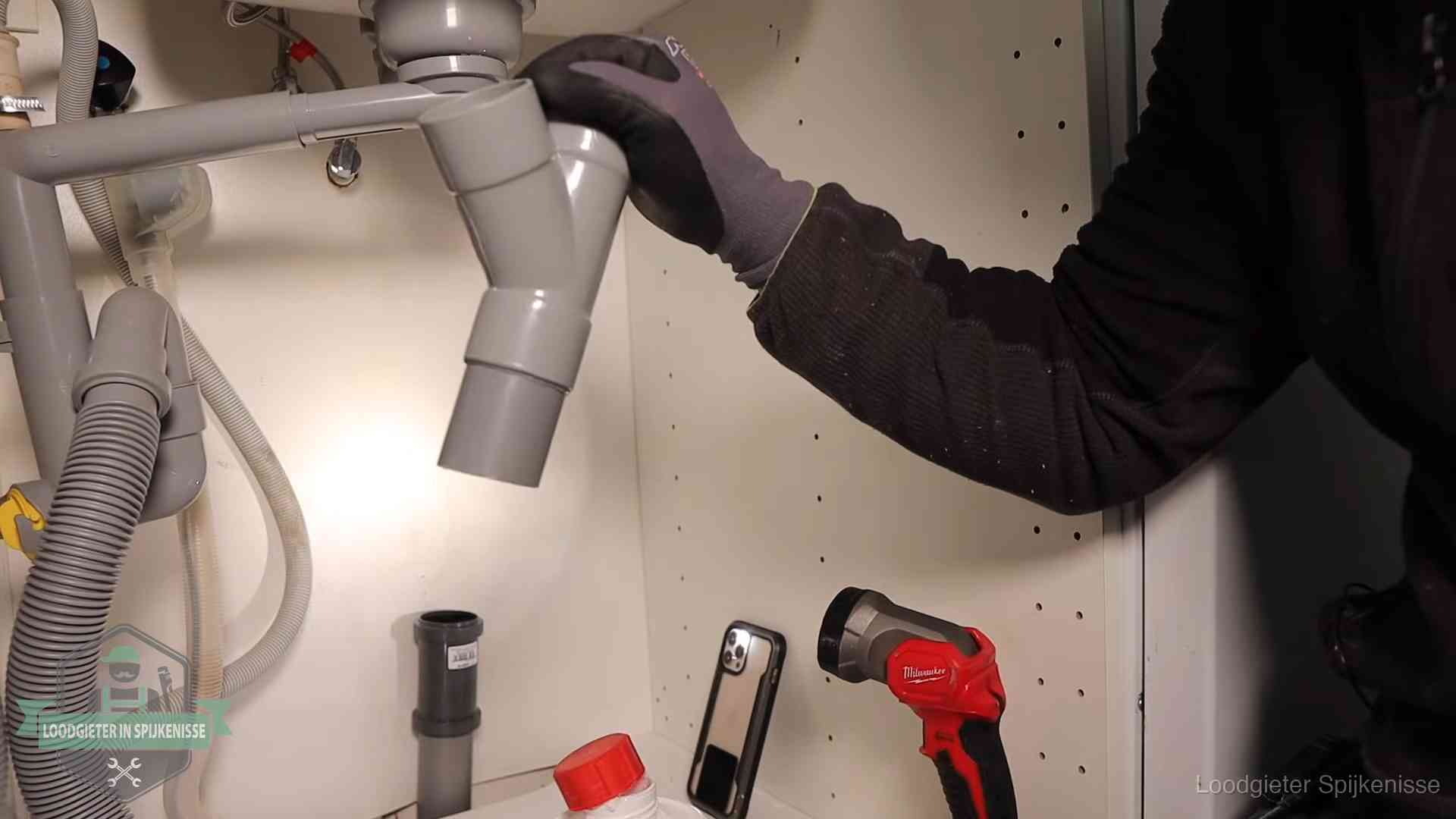 Loodgieter demonteert het sifon- en afvoerwerk onder een gootsteen in Spijkenisse bij stankklachten