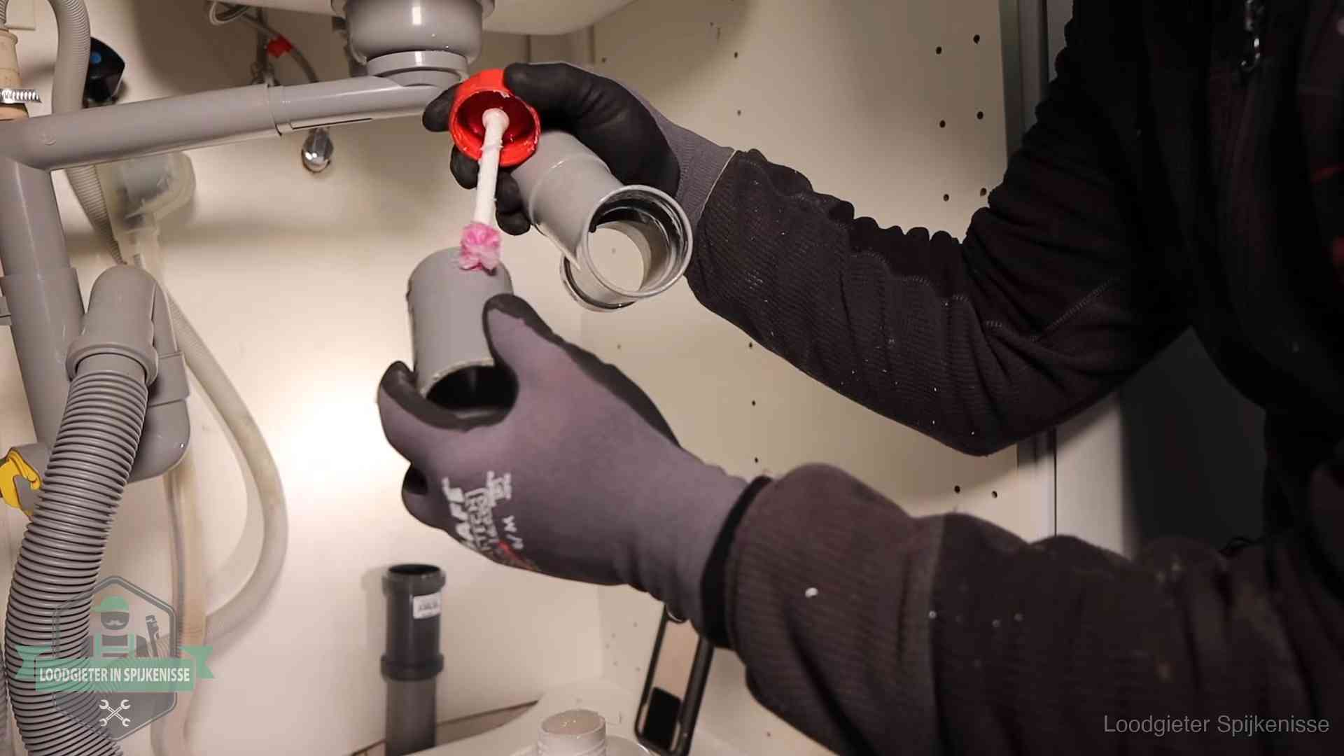 Loodgieter demonteert en reinigt de sifon onder een keukenkast in Spijkenisse