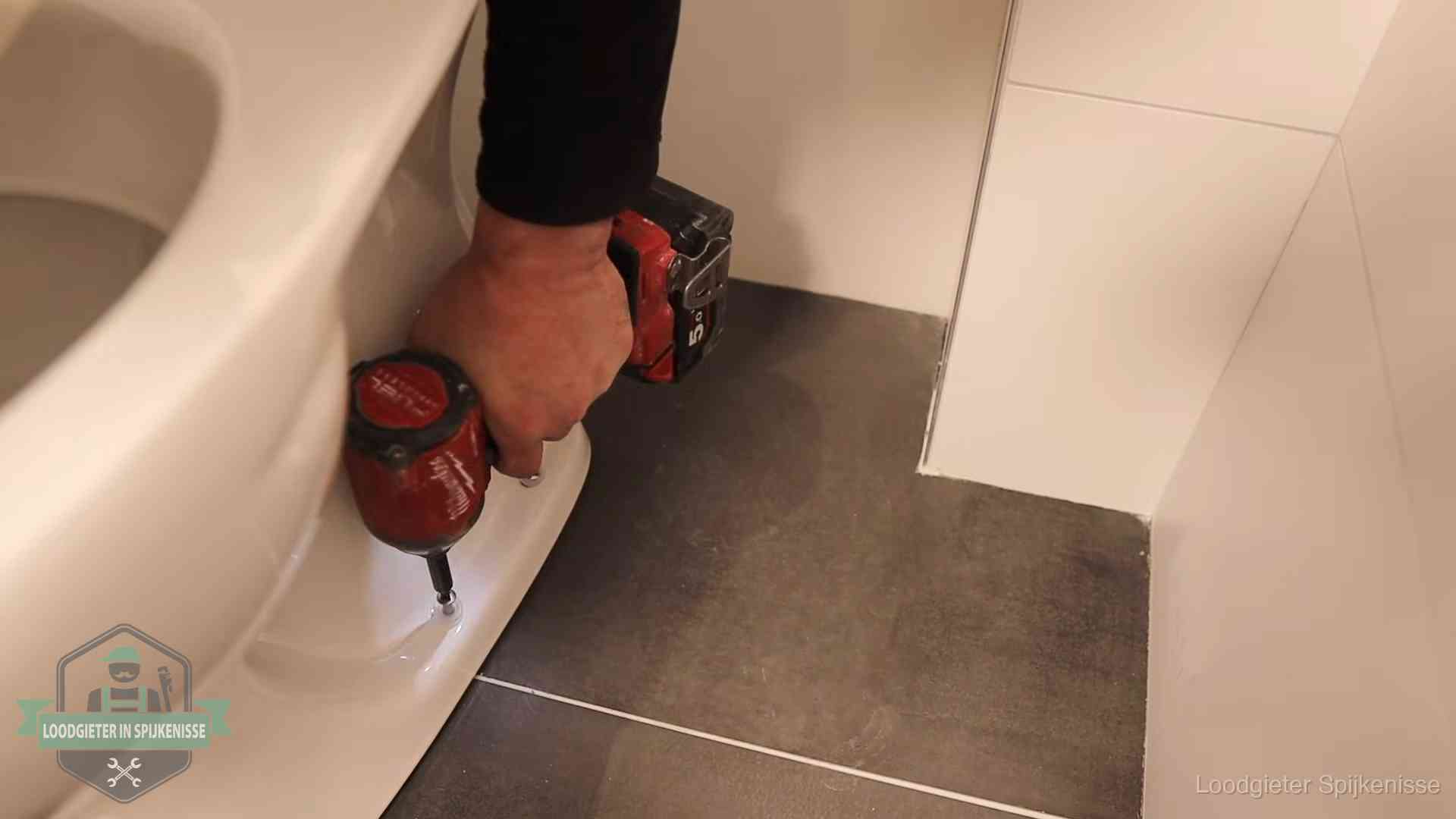 Kosten wc ontstoppen in Spijkenisse Loodgieter zet de voet van een wc-pot vast op de tegelvloer in Spijkenisse